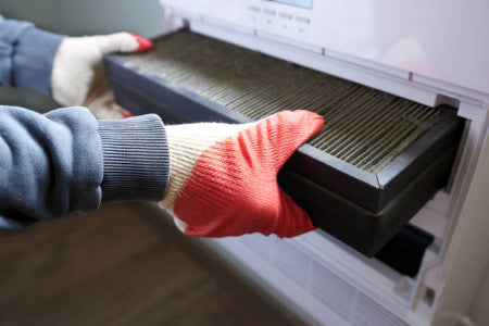 Person wearing gloves removing an air filter from a device
